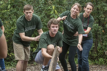 students collaborate during a team building exercise in the woods