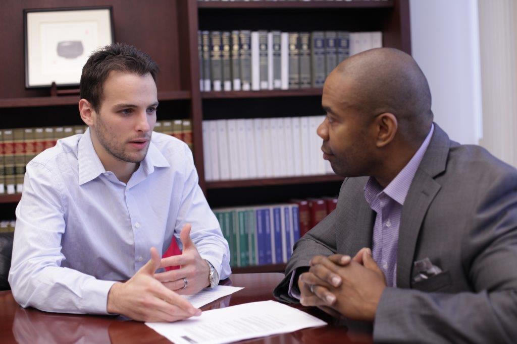 John Volk, '13, speaking with IJ Clinic client Ken Coats, founder of KenTech Consulting.