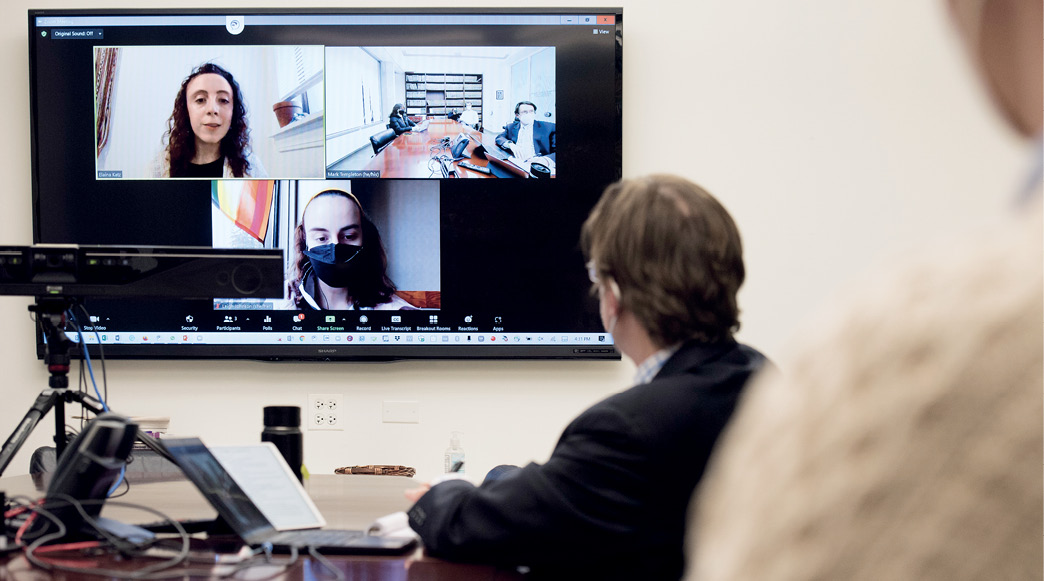 Students are displayed on a TV via Zoom with Professor Mark Templeton in-person in the foreground