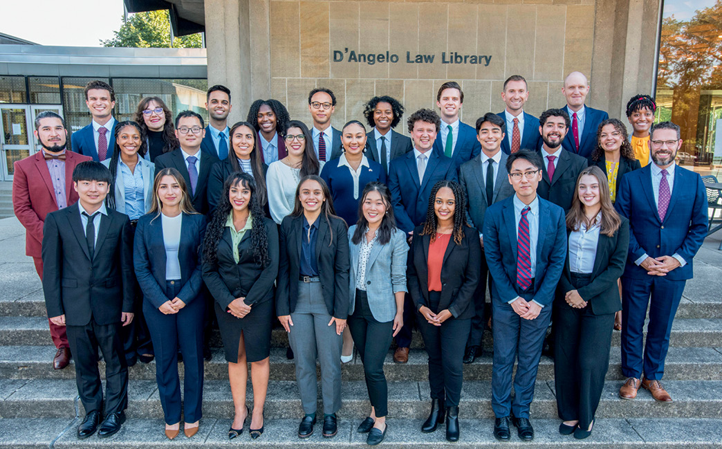 Two dozen students and administrators in professional attire pose for the camera