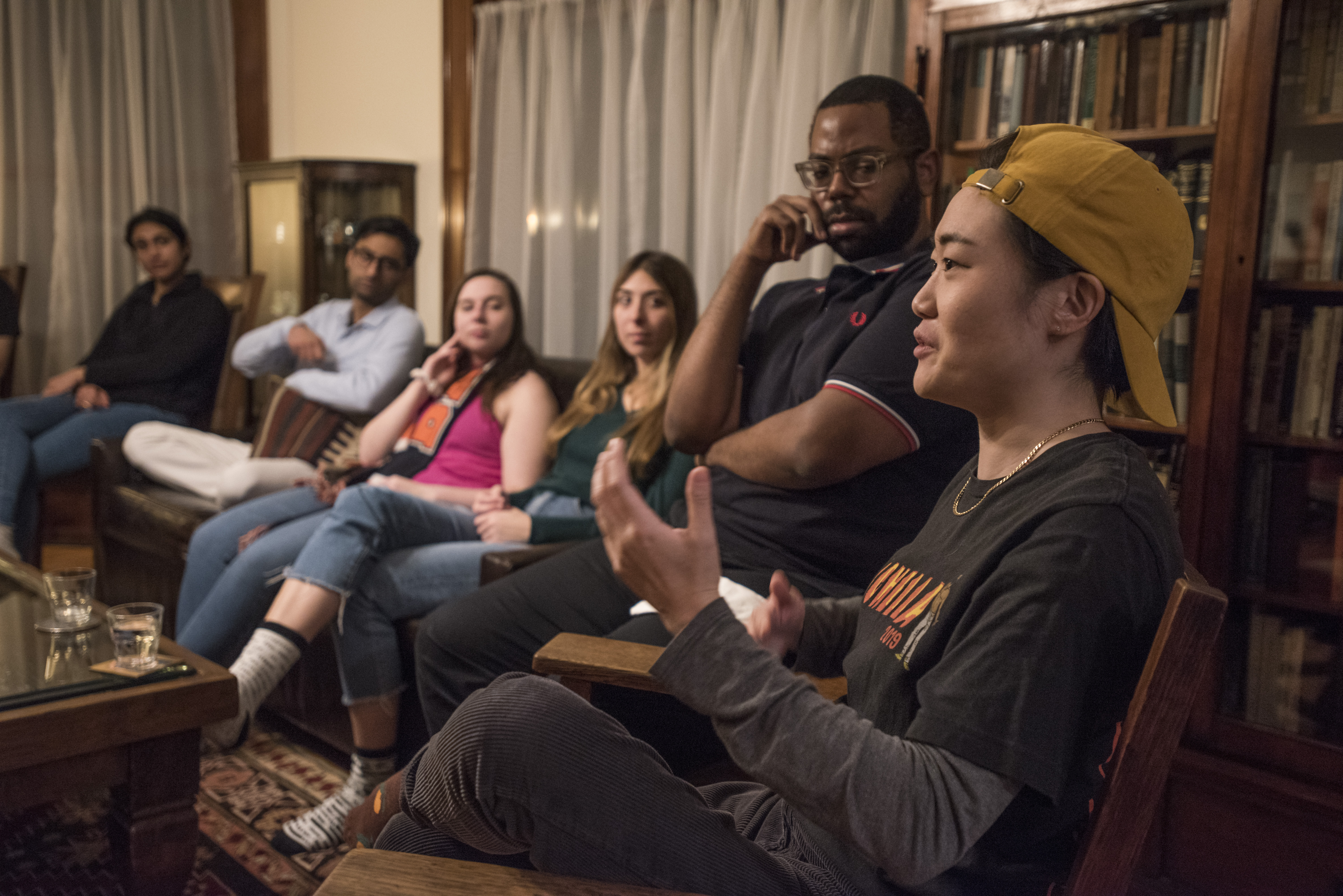 Students listening attentively to another student. They're still in a living room.