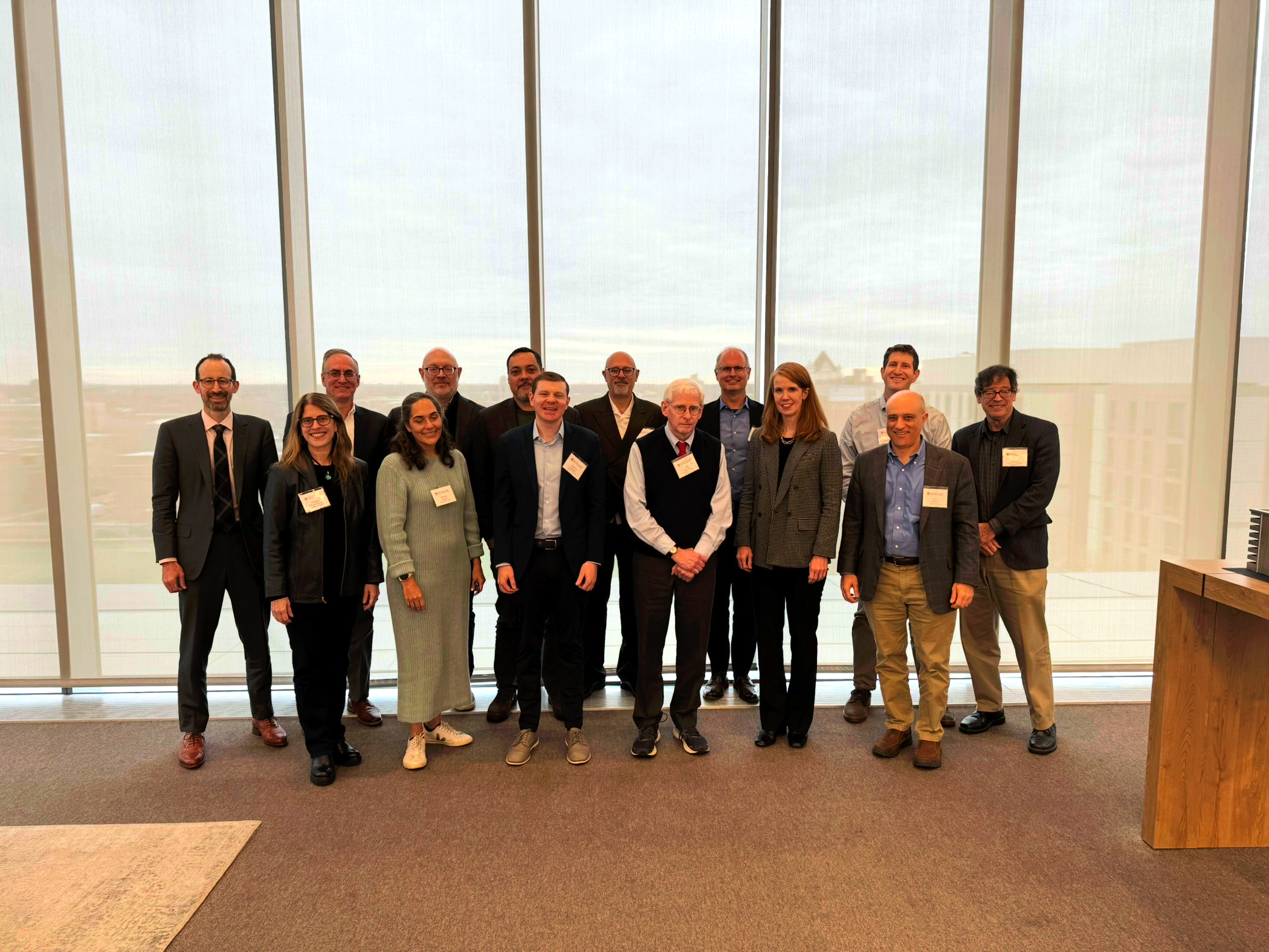 A dozen conference participants with nametags stand for a group photo.