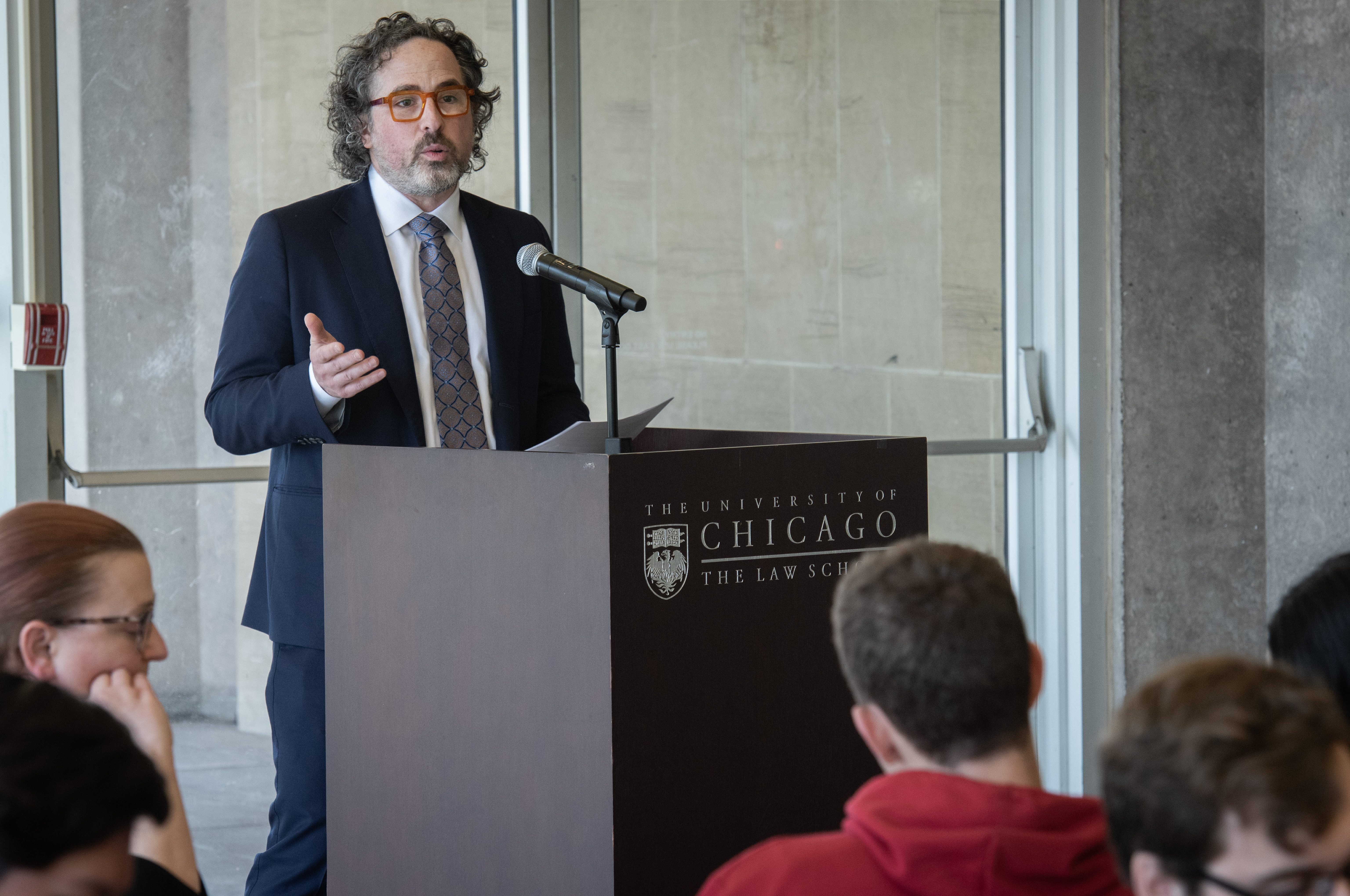 A man stands at a lectern addressing an audience.