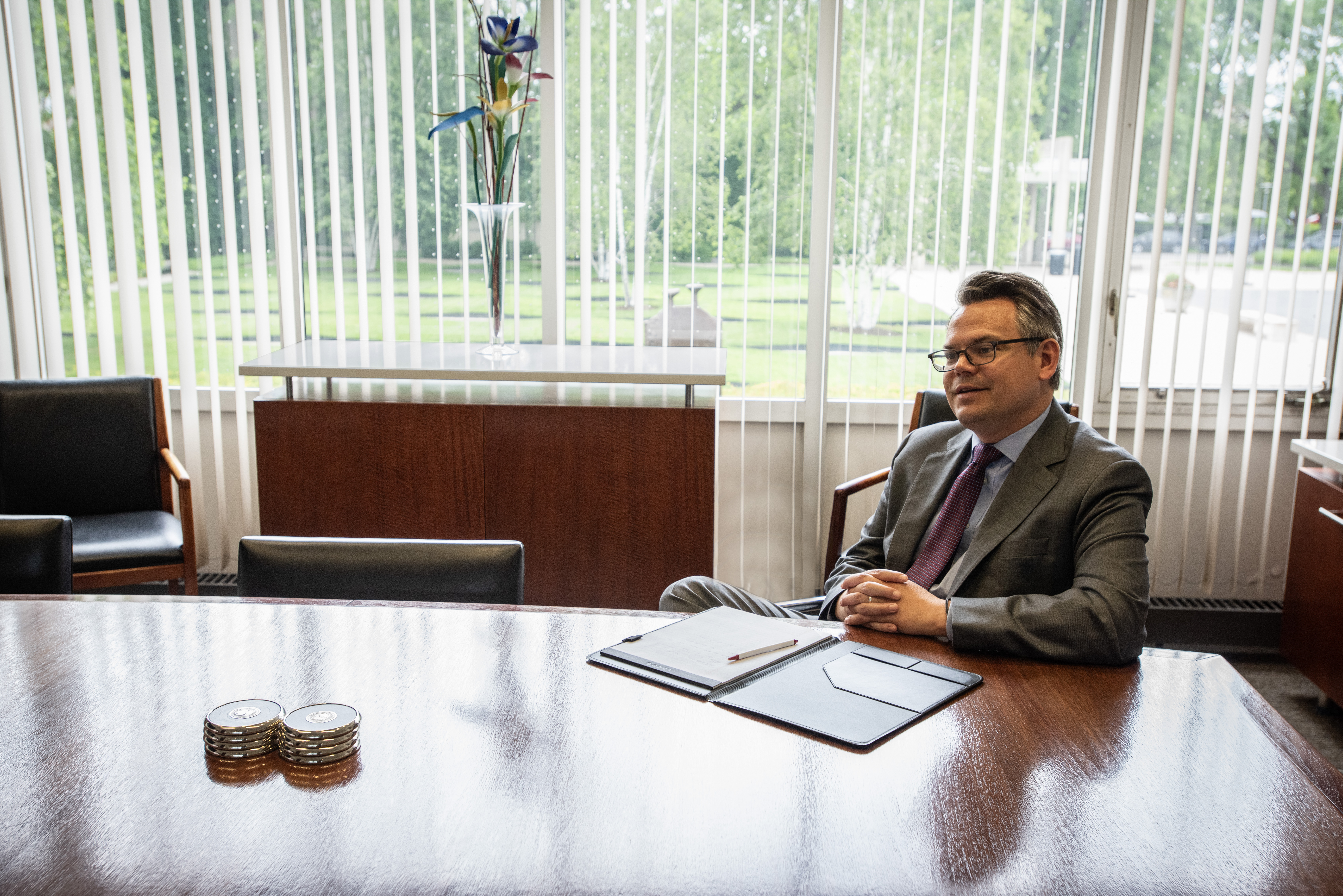 A man in a suit sits at a long conference table.