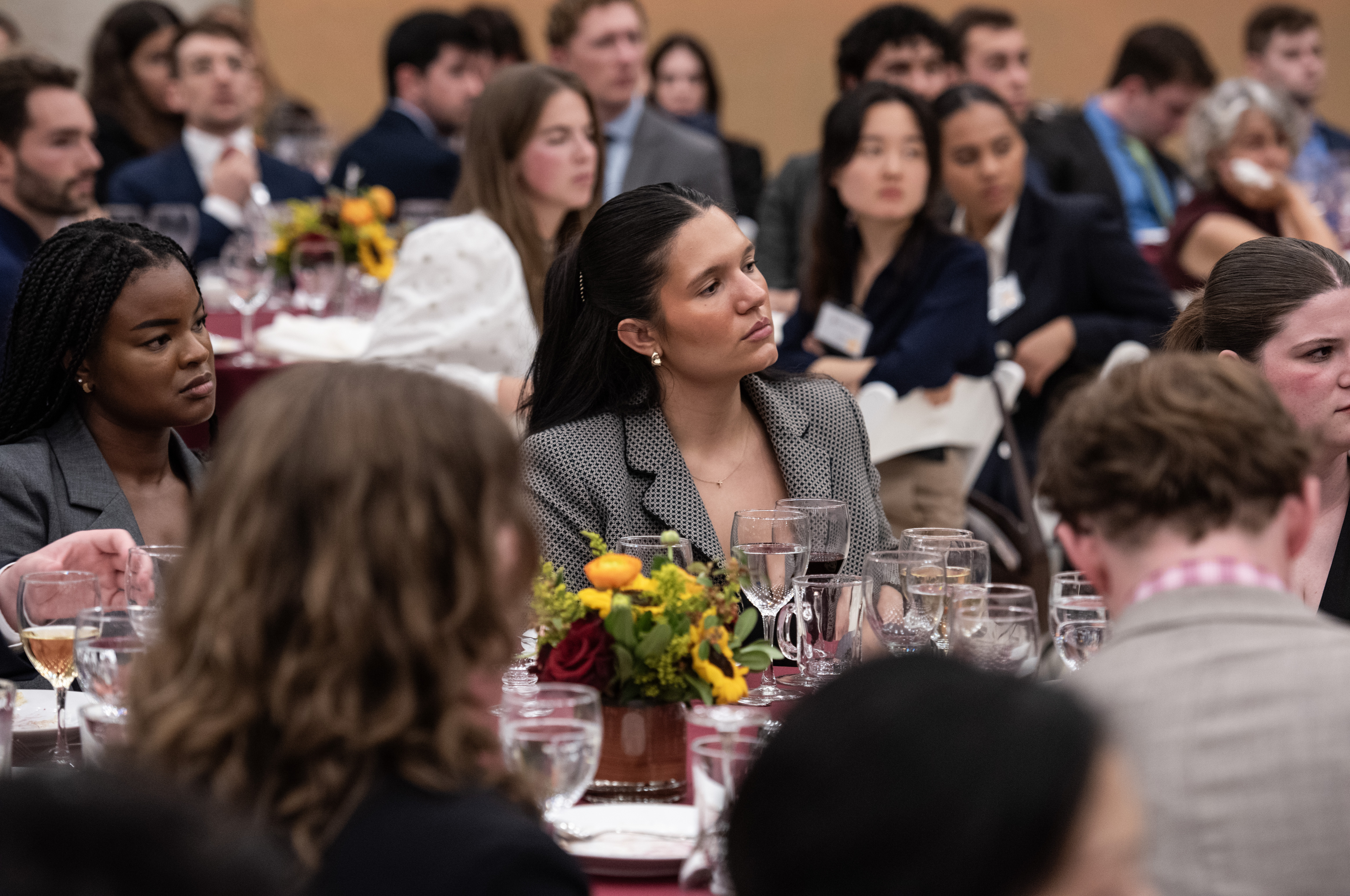 Students sitting at round tables listening intently to the speech