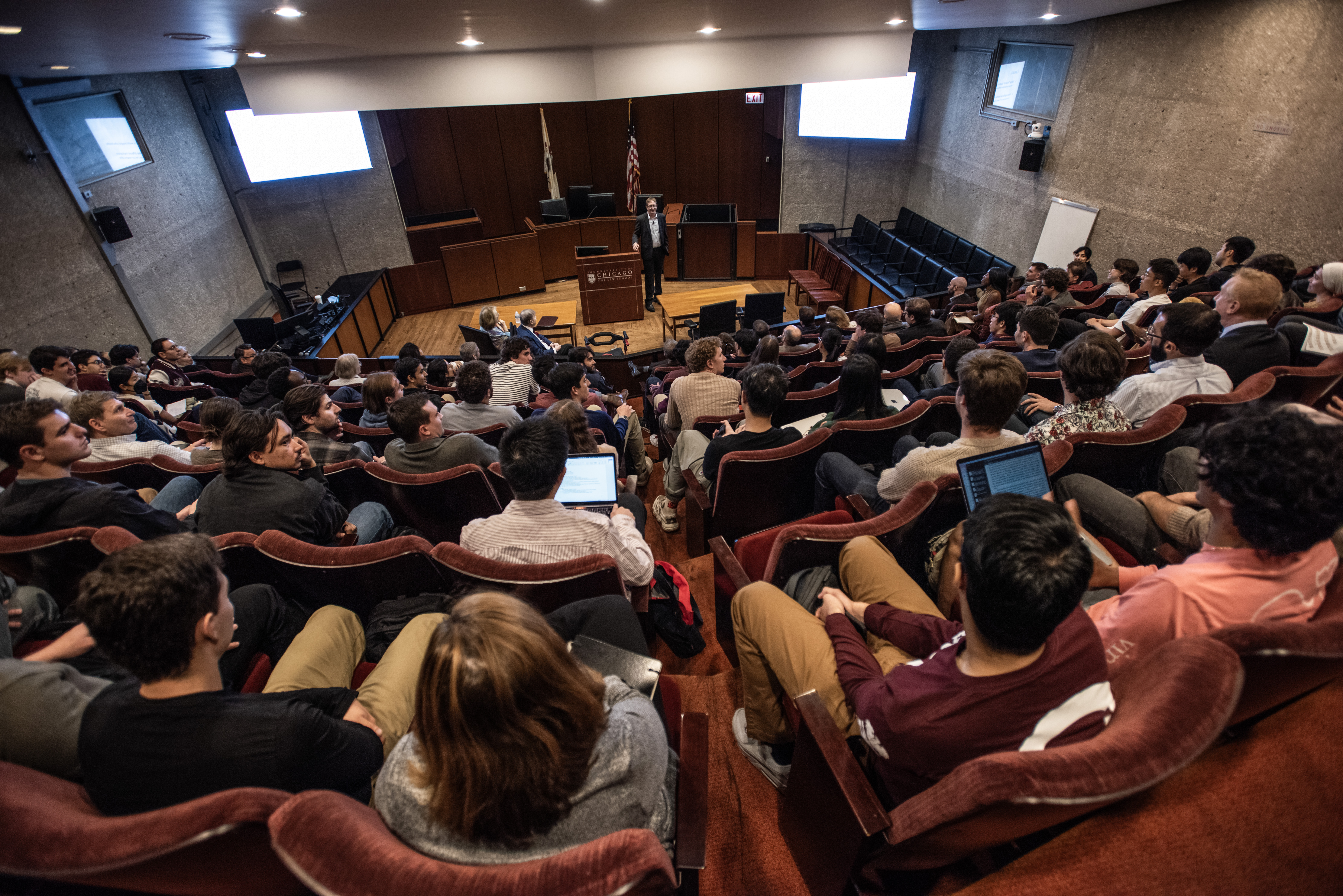 A aerial view of an amphitheater packed with people who are listening to the lecture.