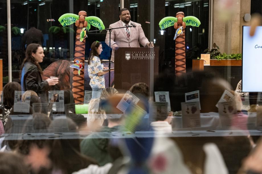 Speaker at the podium addressing an audience. Tropical background theme: palm trees and parrots.