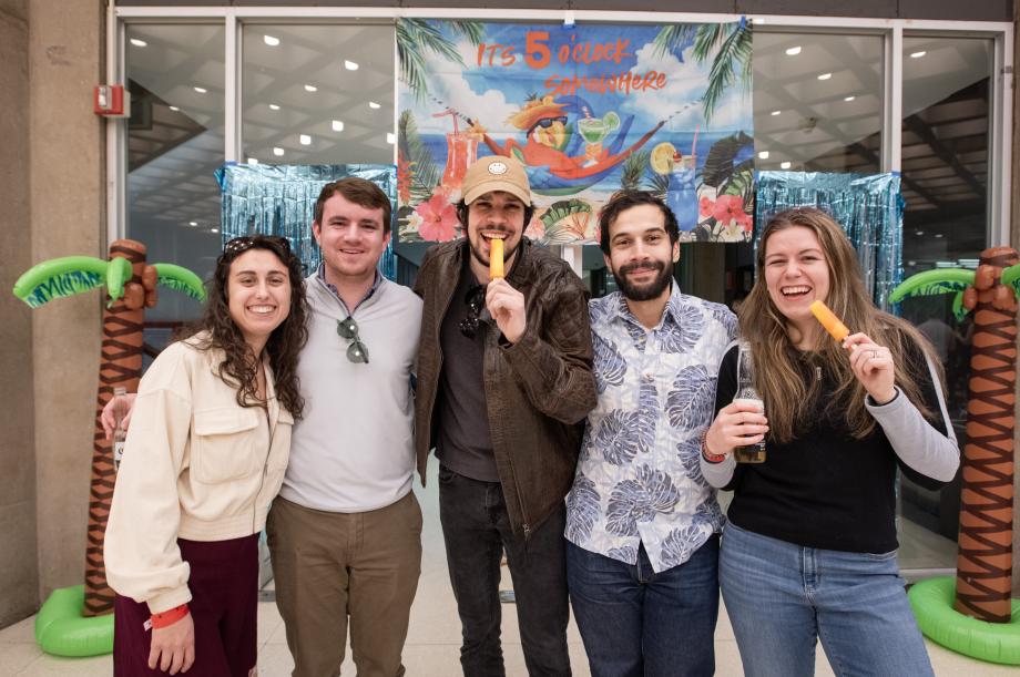 Five students with popsicles and drinks in front of banner that says "It's 5 o'clock somewhere."