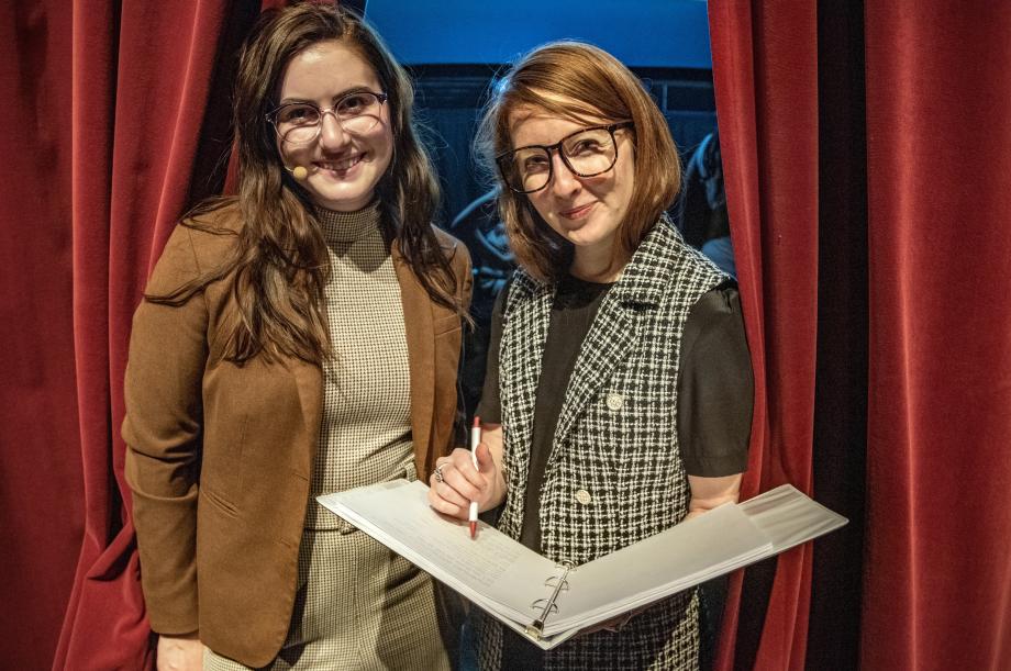 Two people, with one person holding a pen and a binder.