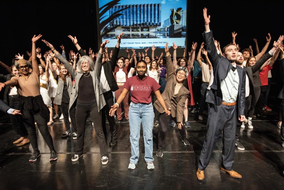 The entire cast with their arms raised cheerfully.