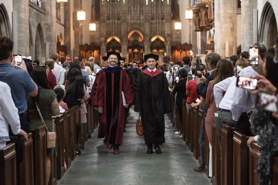 The graduates proceeding into Rockefeller Memorial Chapel, led by Dean Thomas J. Miles and Professor Jonathan Masur.