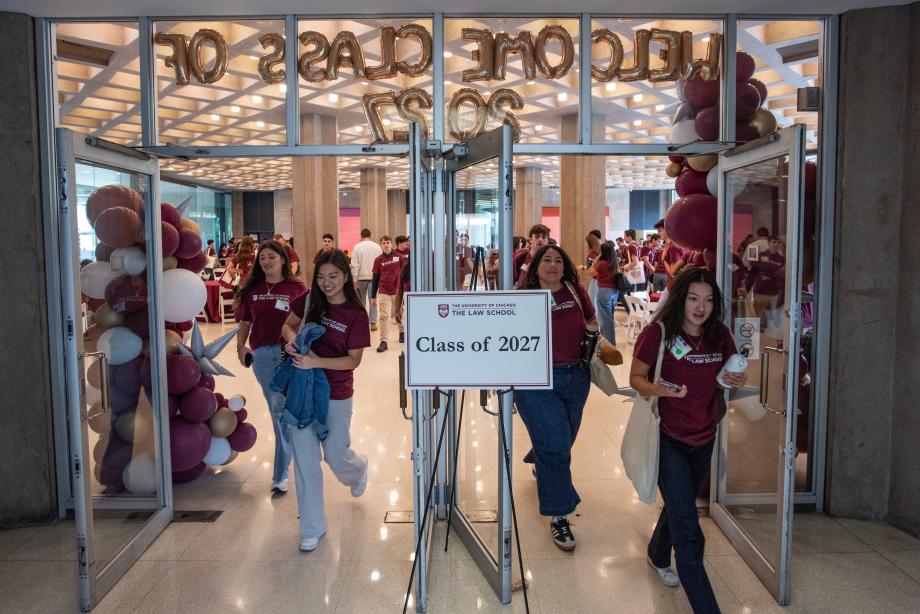 A poster board reads “Class of 2027” as students walk through a doorway decorated with balloons.