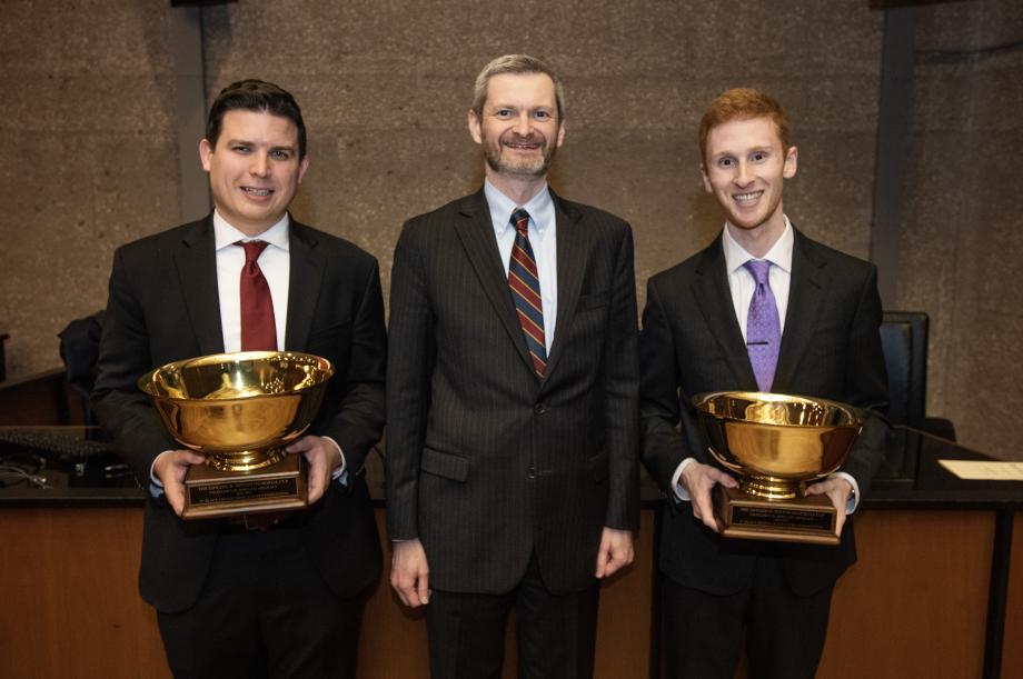 The winning students hold up their trophies in a posed photo with the dean of the Law School, Thomas J. Miles