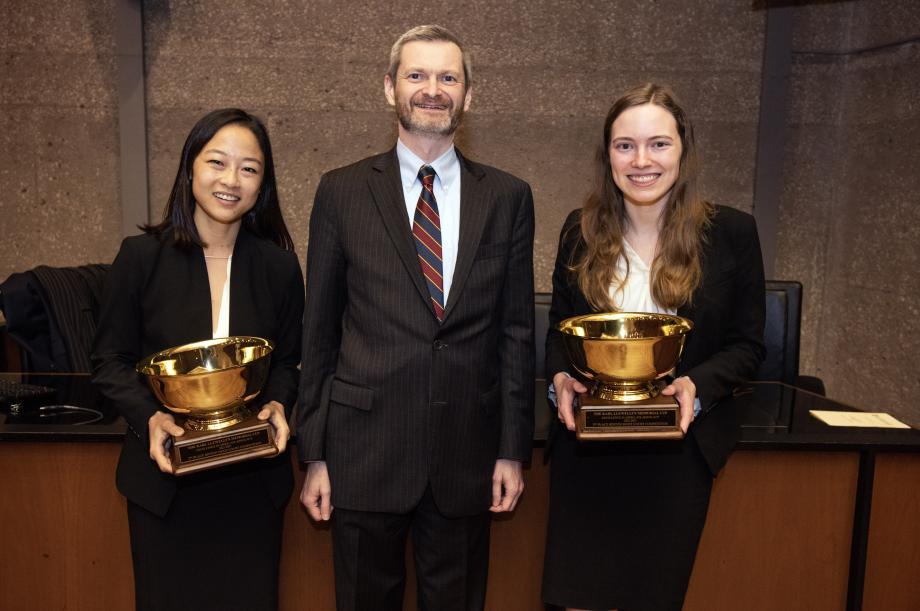 The second place students hold up their trophies in a posed photo with the dean of the Law School, Thomas J. Miles