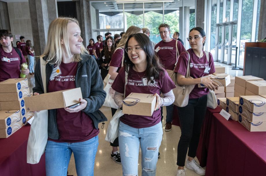 Students carry cardboard boxes as they talk to each other.