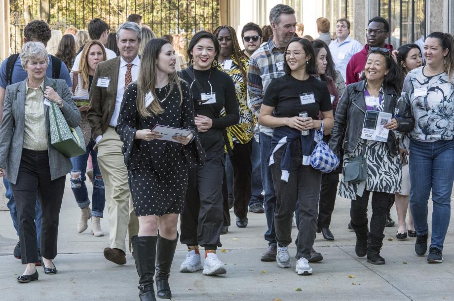 A large group walks beside the reflecting pool outside the Law School.