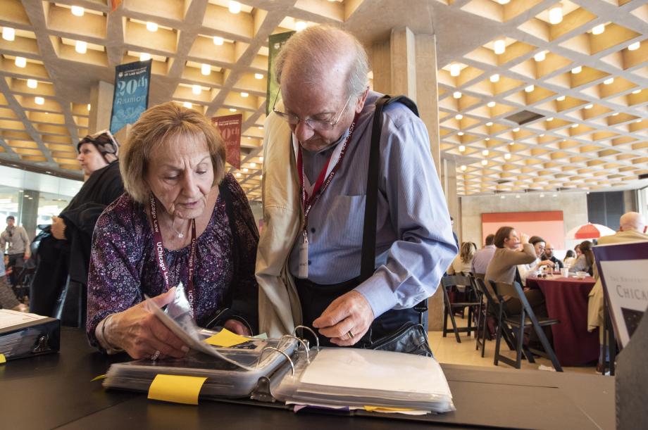 A man and woman review photos in plastic sleeves in a ringed binder.