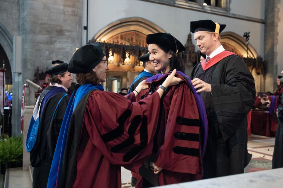 Four faculty members present the graduates with their hoods.