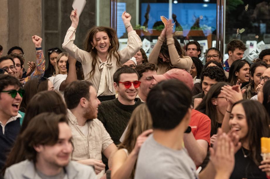 Two students in crowd standing and cheering.