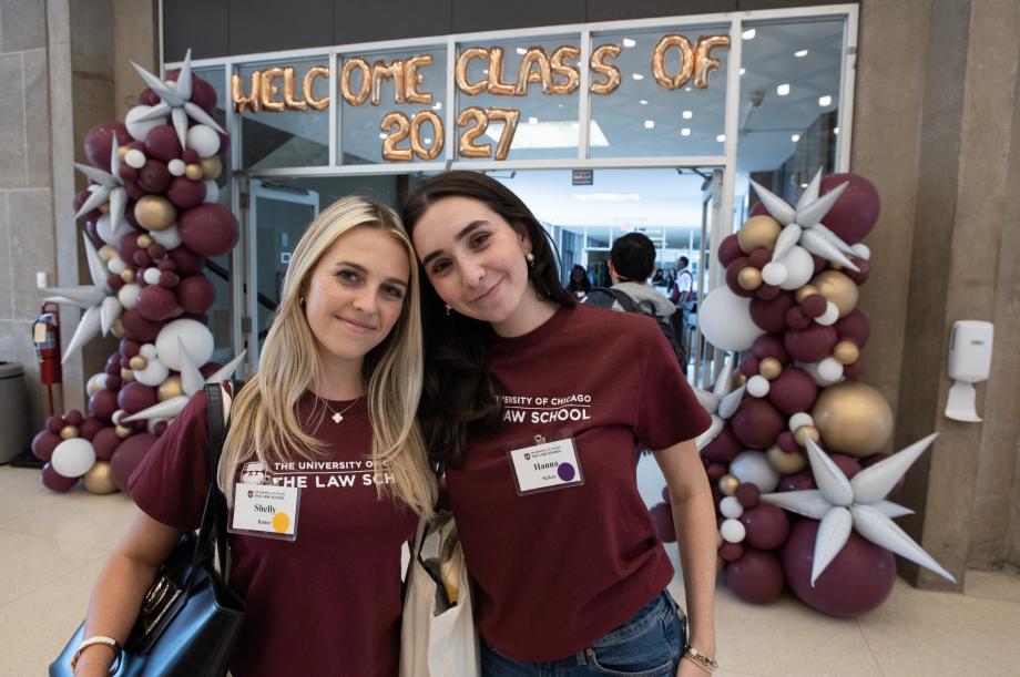Two new students smile for camera with the balloons spelling out “Welcome Class of 2027” behind them.