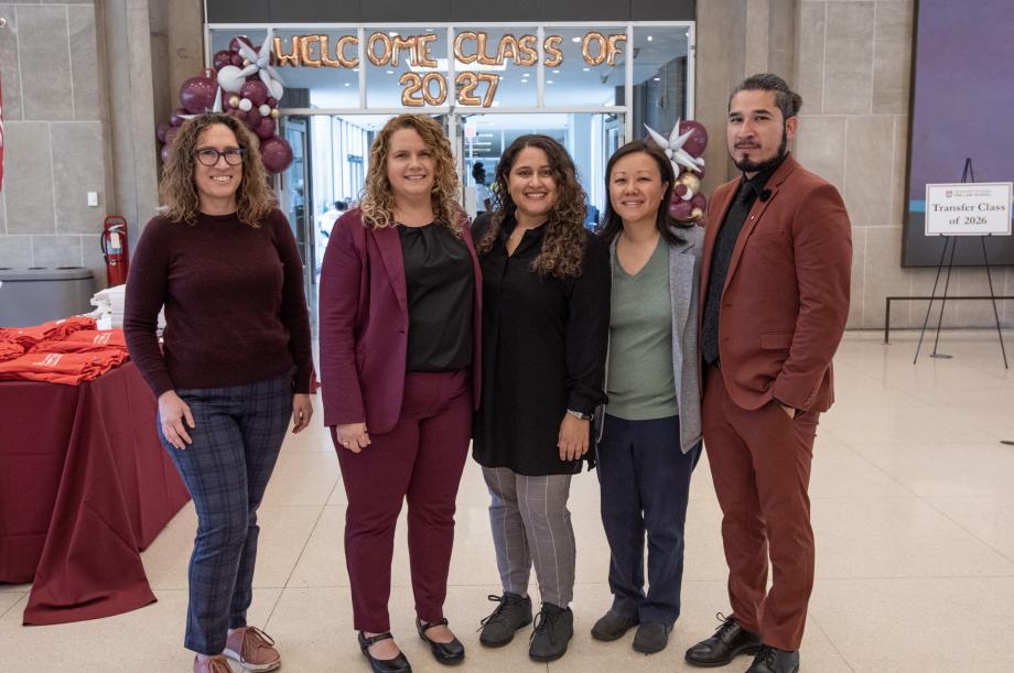 Five smiling staff members in professional attire pose for a group photo. Behind them balloons spell out, “Welcome Class of 2027.”