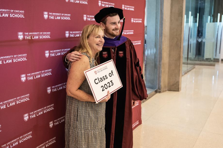 A graduate and a family member pose for a photobooth holding a sign that says Class of 2023.