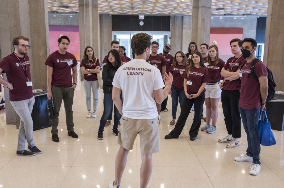 An Orientation leader stands facing a group of new students and speaks to them in the Green Lounge.