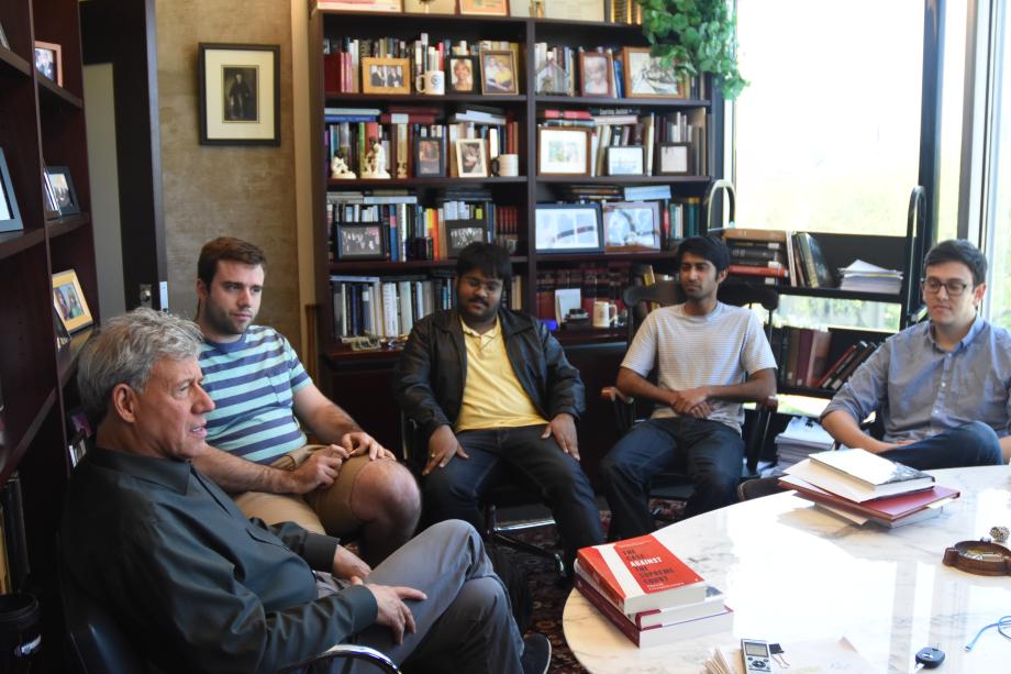 Four students are seated looking at Stone, also seated in the semi-circle.