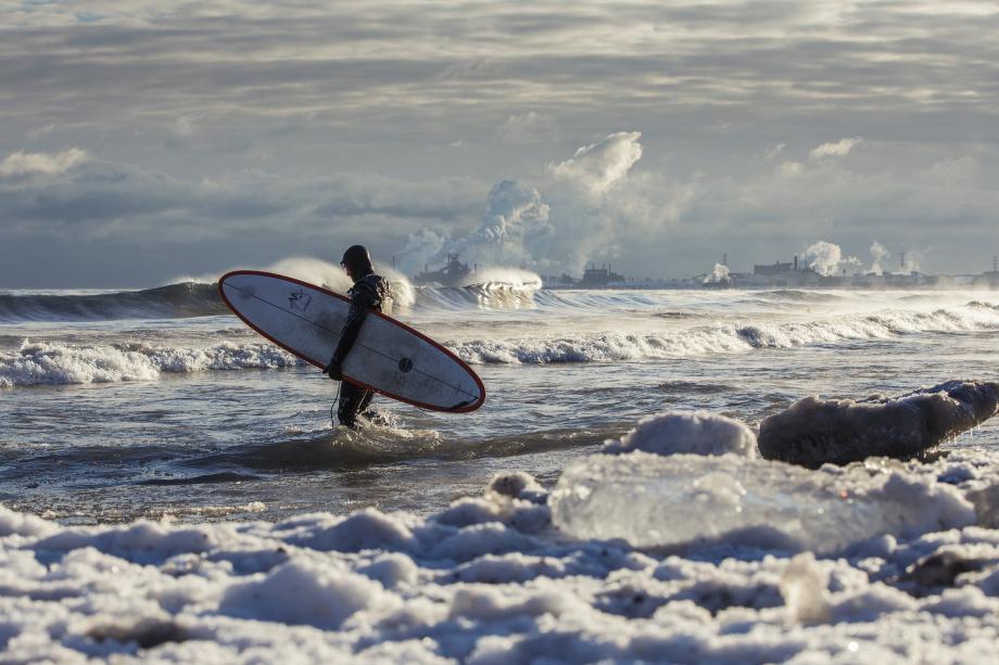 Surfer in front of factories