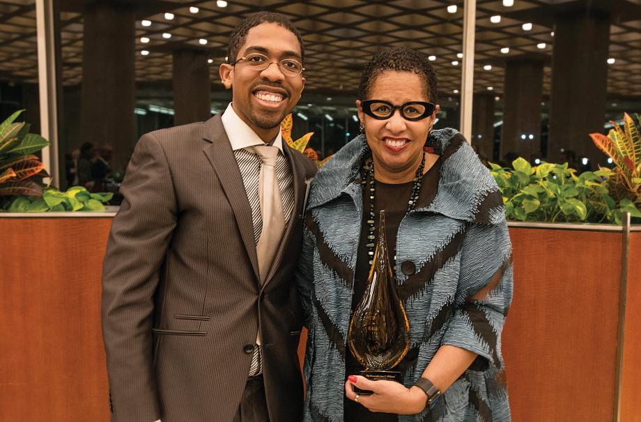 André J. Washington and Judge Ann C. Williams, holding a trophy, pose for the camera