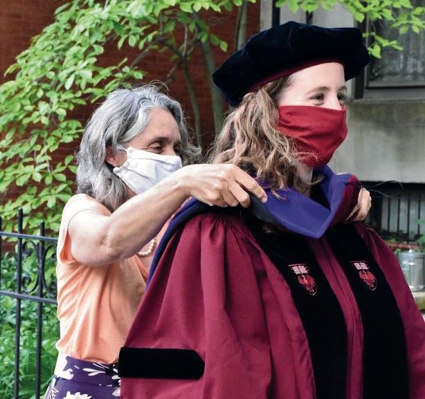 Jen Herrmann in regalia being hooded by Emily Buss