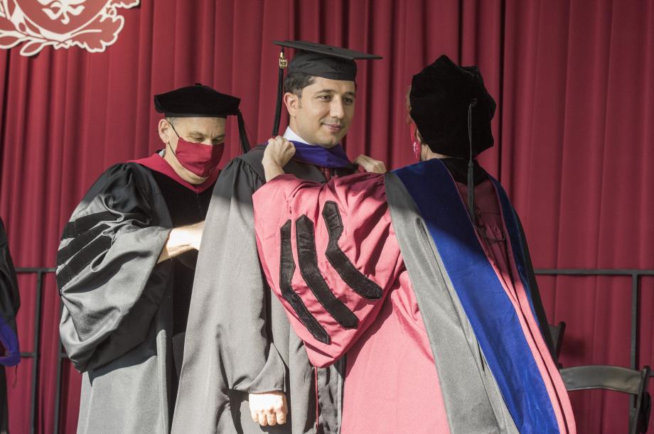 The four faculty hooders—Emily Buss, David Strauss, Genevieve Lakier, and Jonathan Masur—placed the traditional hood.
