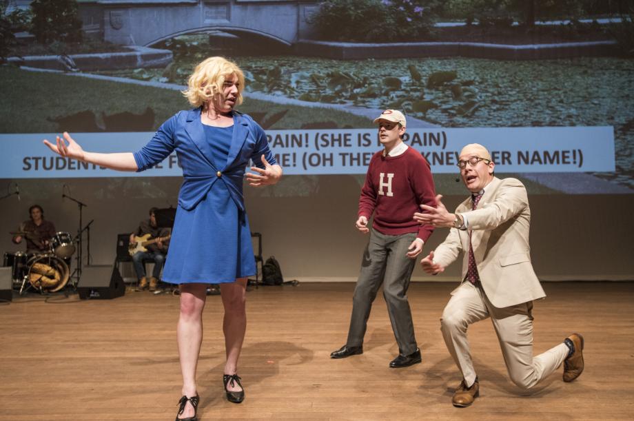 The student playing Nussbaum, dressed in a blue suit, sings to the students playing Eric Pawsner (standing) and Saul Levmore (in a tan suit, on one knee).