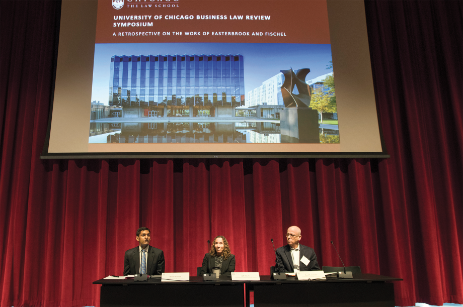 Professors sitting below a screen that says "University of Chicago Business Law Review Symposium: a Retrospective on the Work of Easterbrook and Fischel"