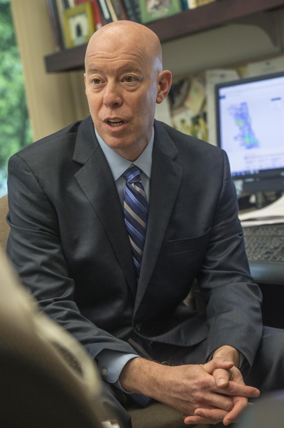 Full color photo of Craig Futterman facing away from a computer to talk to someone off camera.