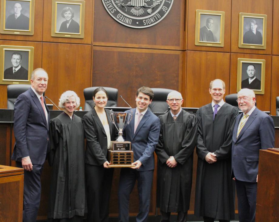 Students hold their trophy flanked by judges and co-chairs of the competition