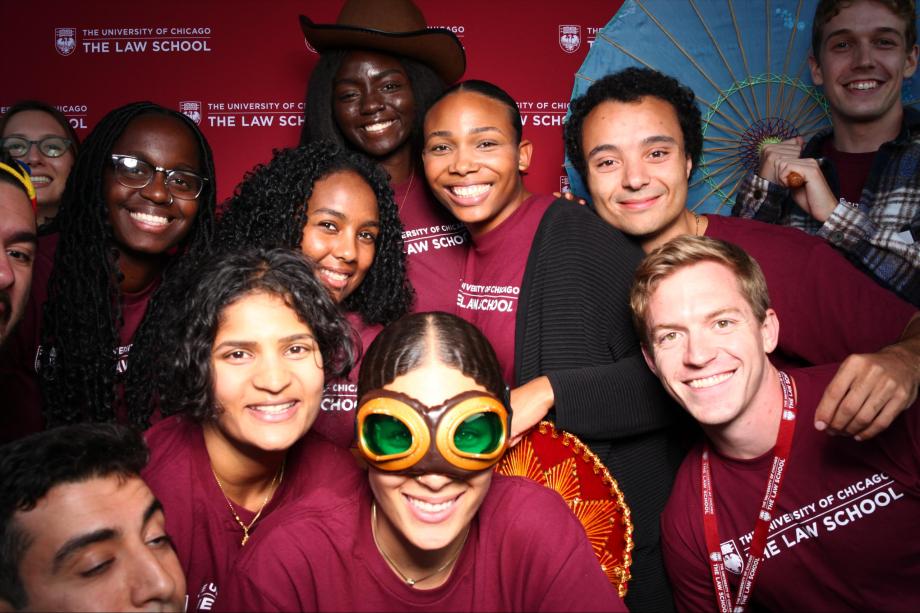 Multiple people pose in front of a branded backdrop with props.