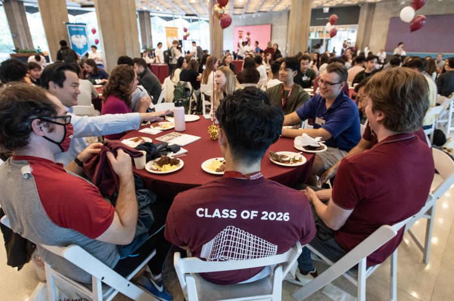 Students sit around a round table with food on their plates