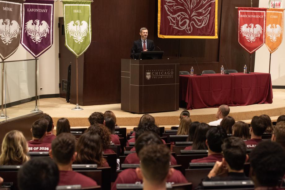 Dean Miles stands behind a podium in the auditorium with students seated in the foreground.