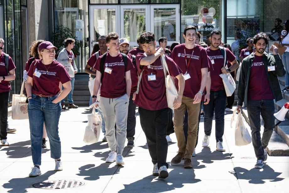 Students in their matching t-shirts and tote bags walk outside the Law School.