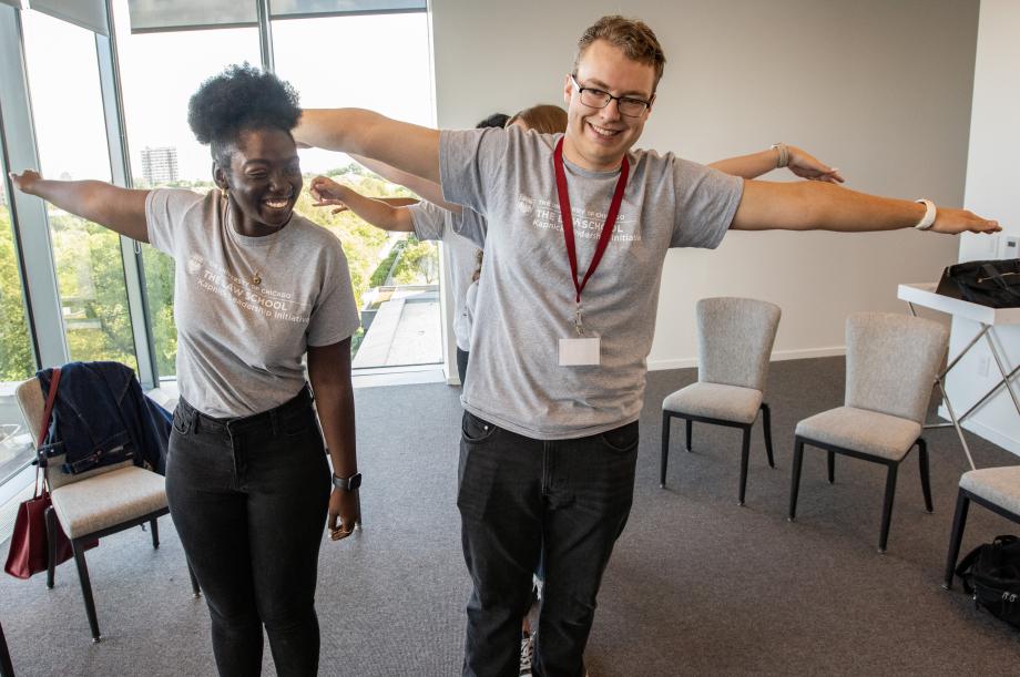 Several students stand in a line with their arms outstretched.