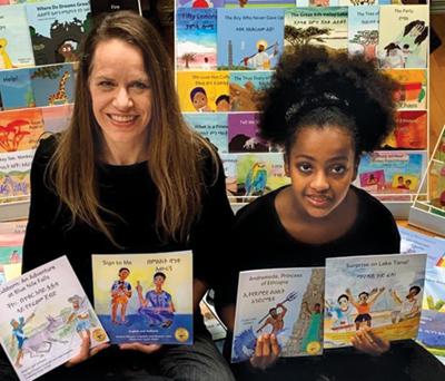 Ellenore Angelidis and daughter sit surrounded by childrens' books.