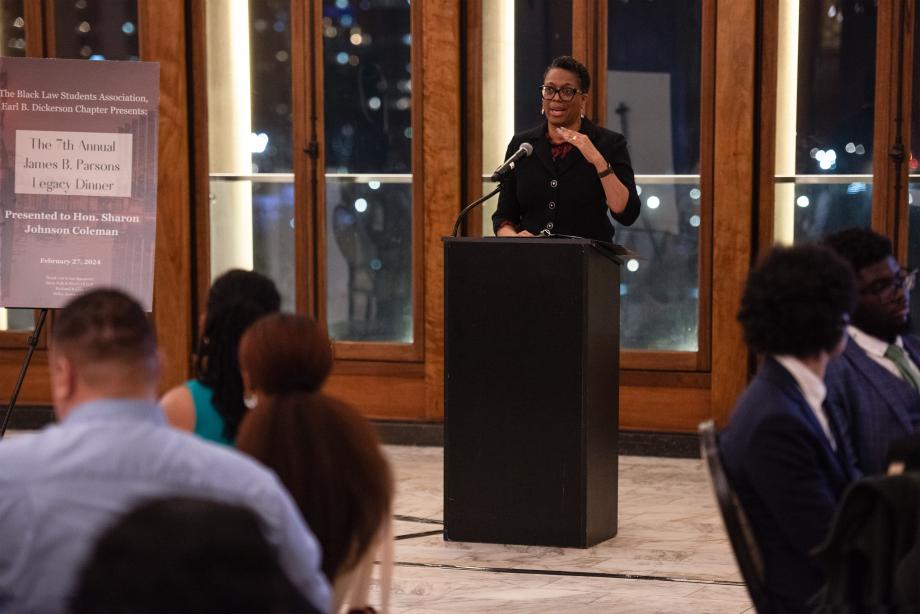 Sharon Johnson Coleman speaks from a podium with a seated audience gazing at her.