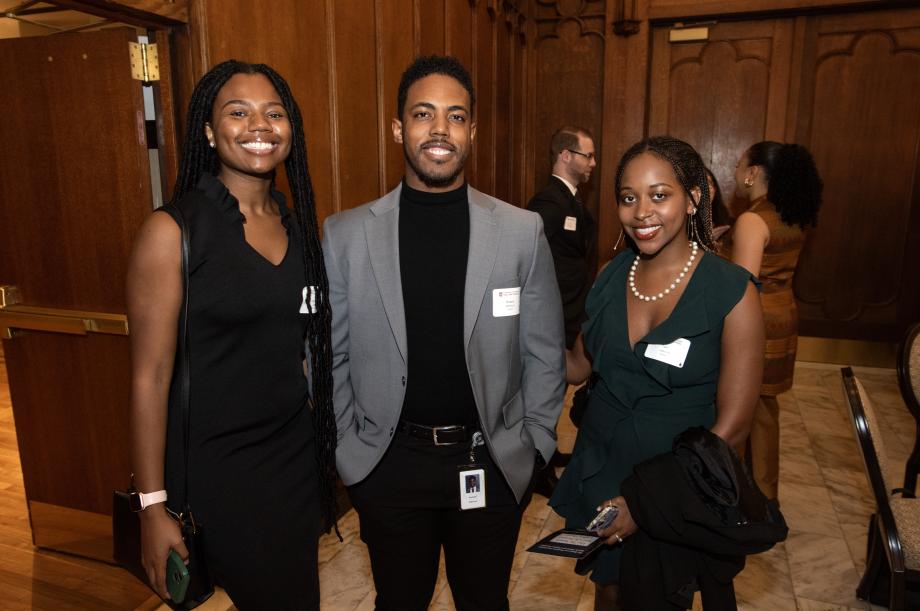 Three students in formal attire smile at the camera.