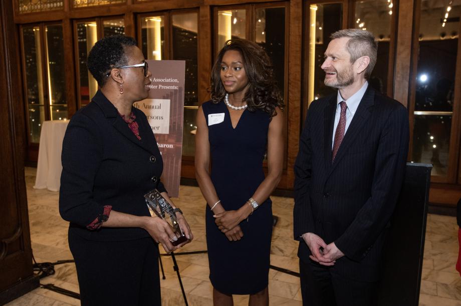 Sharon Johnson Coleman holds a glass award as Faith Udobong and Thomas Miles engage her in conversation.