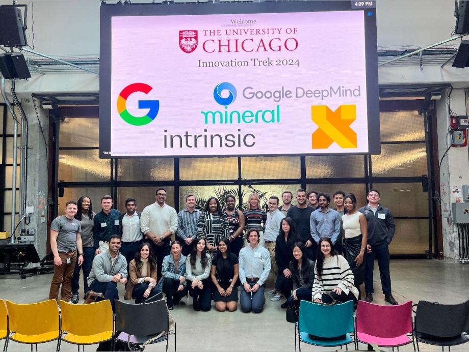 People standing together for a photo in front of a large screen.