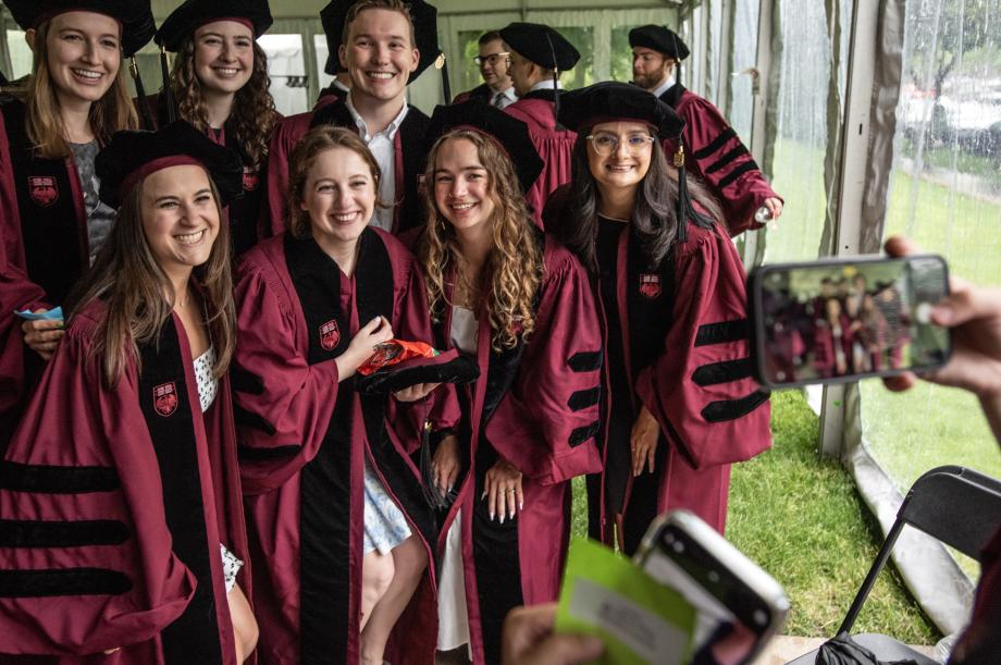 Students shelter under a tent, posing for a group photo.