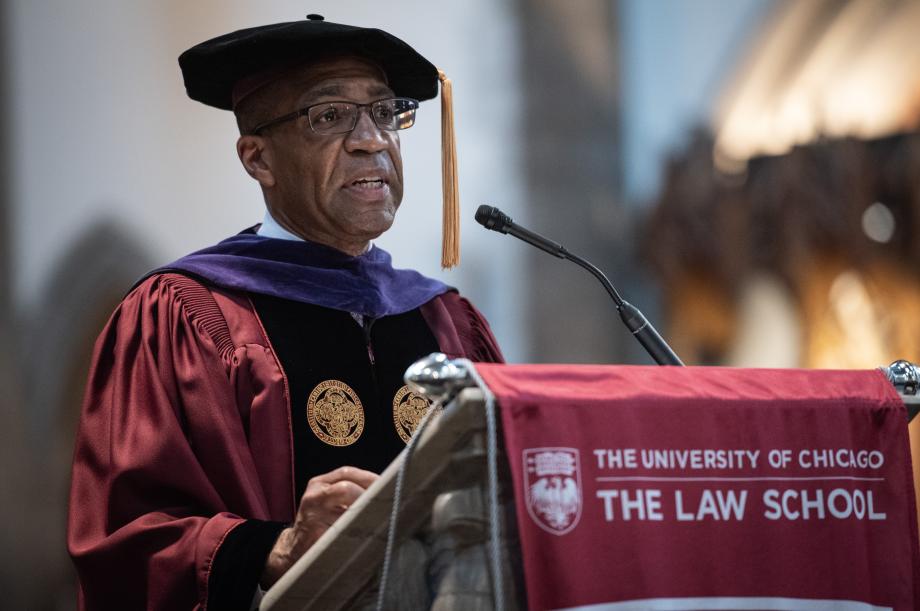 Barry Fields, in a cap and gown, speaks from the podium.