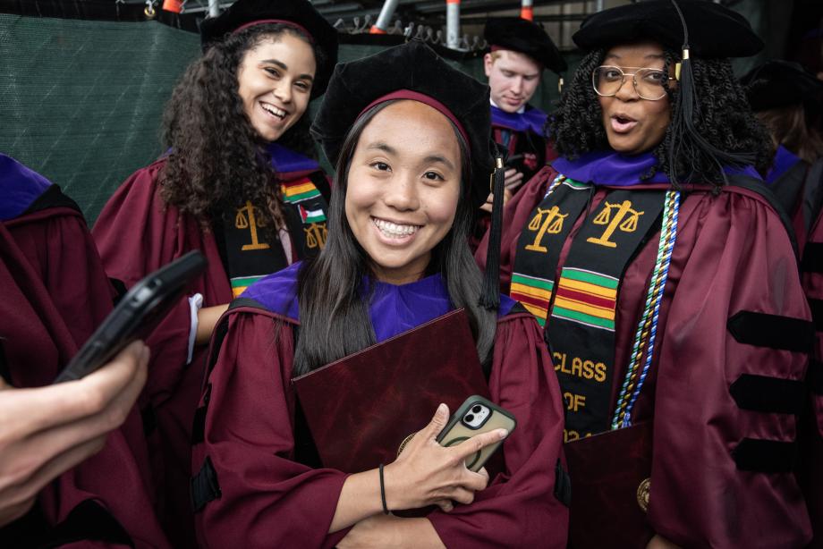 A student, surrounded by peers, smiles widely at the camera.