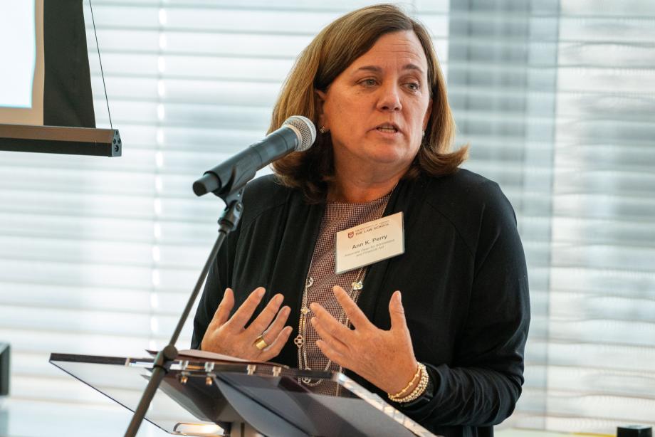 Ann K. Perry, associate dean for admissions and financial aid, spoke about her experience with Rubenstein Scholars over the years. Ann Perry speaking at a microphoned podium gesturing with her hands facing upwards while talking about the Rubenstein Scholars program
